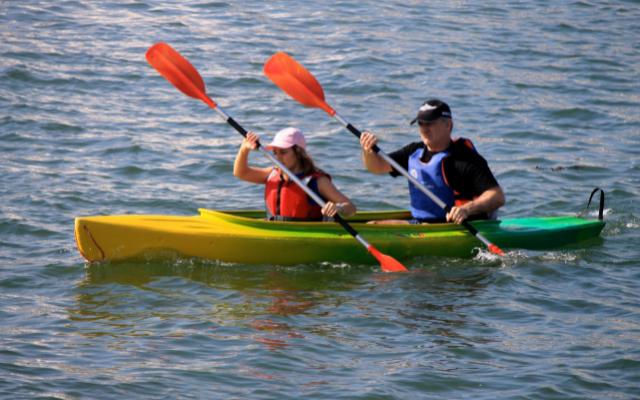 Two paddlers using double-bladed paddles in a tandem kayak