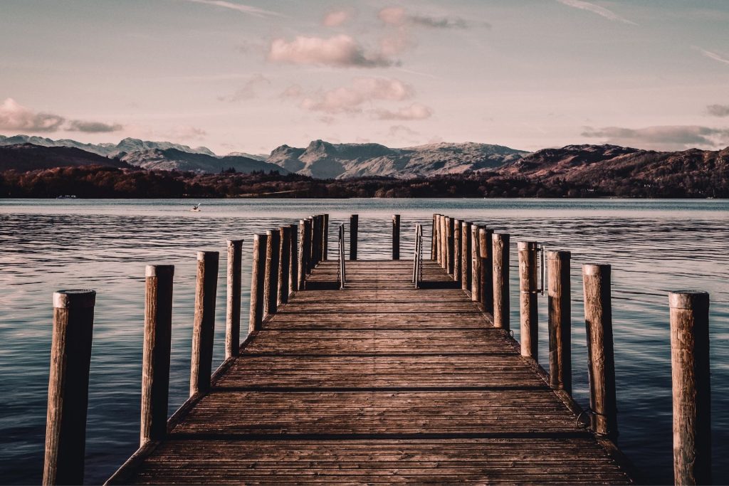 Wooden jetty extending into Windermere with fells beyond