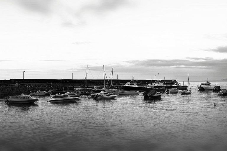 Small boats moored beside a stone harbour wall