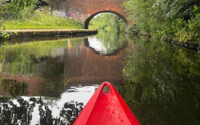 View from a red kayak towards a brick canal bridge