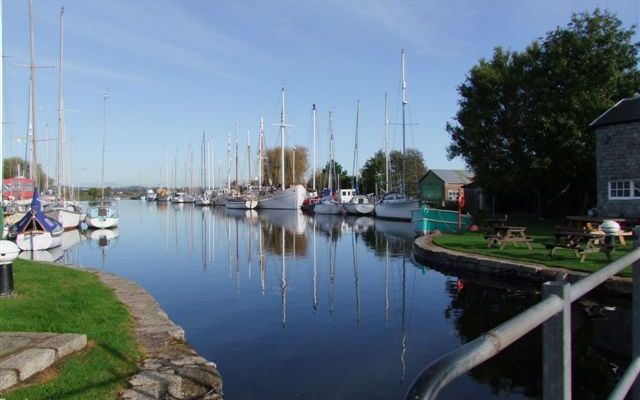 Moored sailing boats beside a grassy waterside bank