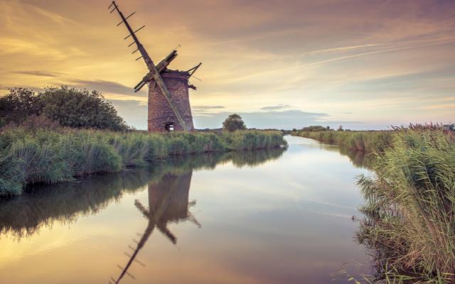 Windmill reflected in a reed-lined waterway on the Norfolk Broads
