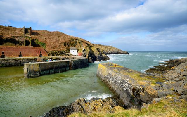 Stone harbour walls and rugged Pembrokeshire coastline
